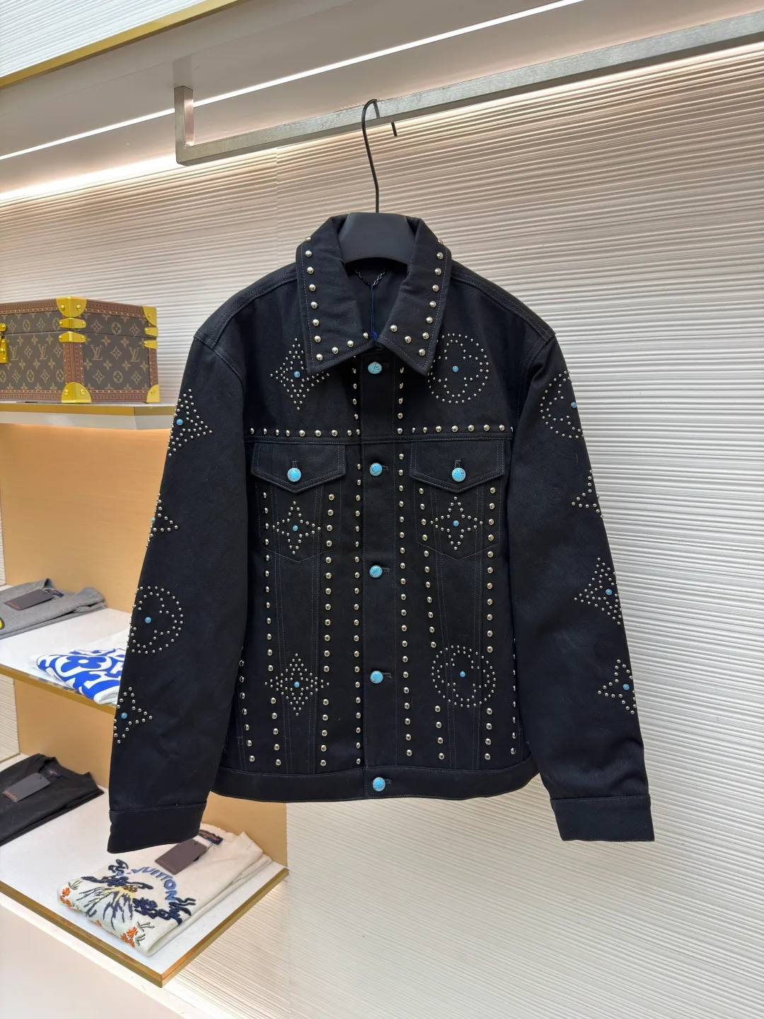 LOUIS VUITTON turquoise rivet denim jacket ●Original version: purchased and developed by 38979 ●Item number: 1682224-E30 ●Material: denim fabric ●Technology: hand-made rivet inlay ●Color: black ●Version: fitted version ●Weight: about 1550 grams ●Size: 46-48-50-52 ●Description: This black denim jacket is made of high-density twill denim fabric and has been treated with pre-washing water. It not only retains the crisp texture of the fabric, but also achieves a soft and skin-friendly wearing experience. The entire body of the garment is made of hand-made rivet inlay technology. The metal rivets are arranged at precise points to outline the outline of the brand's classic logo. Each rivet is manually hammered and fixed to ensure firmness and three-dimensionality. The placket and pockets are decorated with turquoise-textured resin buttons, which contrast with the metal rivets. The stitching on the collar, cuffs and hem adopts a double stitching process to enhance structural stability, while the edges are roughened to add a retro texture. The overall cut is a slightly loose Oversize version, combined with the three-dimensional tailoring process of the three-dimensional shoulder line, taking into account both styling and wearing comfort. Every detail is calibrated by hand, demonstrating the exquisite level of clothing making technology. The overall wiring is straight and delicate, the fabric is comfortable and soft, and the color is consistent without color difference. It can be matched with the same style to create a fashionable look and control various occasions. Customized accessories, complete with three standards, same style for men and women!